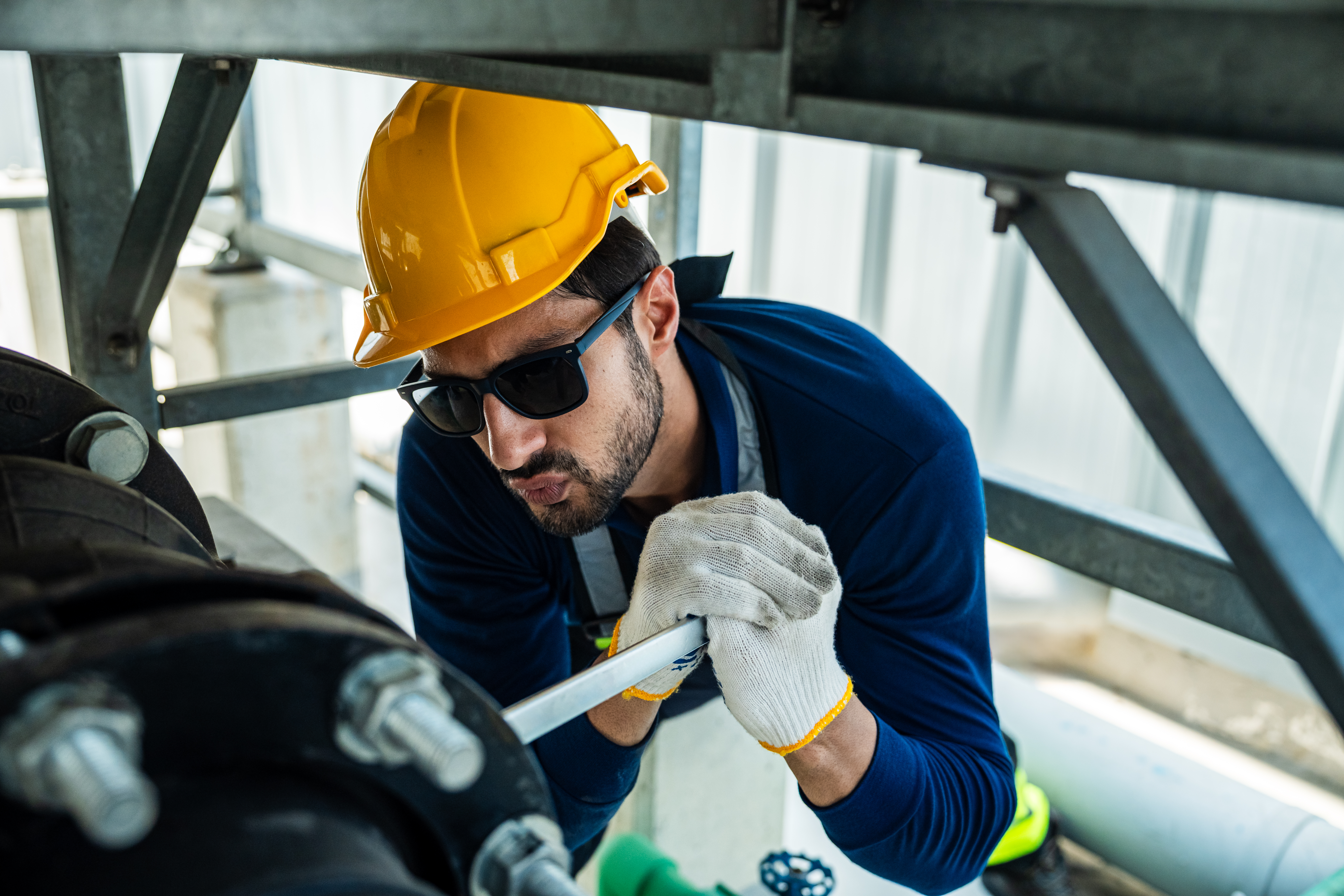 Industrial engineer tightening pipeline valve during cooling tower maintenance procedure. Technician ensures stable performance of factory cooling and water circulation system.